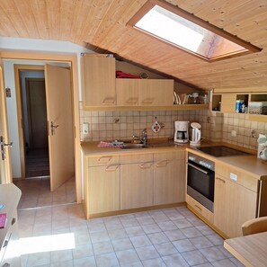 Eine kleine Küche mit Holzausstattung, einem eingebauten Backofen und einem Oberlicht.