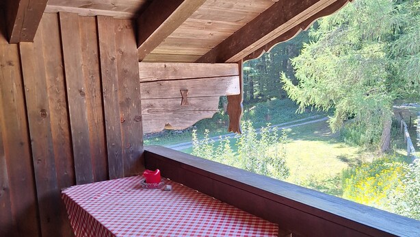 A wooden deck with a table and chairs, a checkered tablecloth, and a view of greenery. - Rauher Kopf Vacation Rental, 50 m², 1–4 people, 2 bedrooms, 2 showers/toilets, kitchen (Bischofswiesen)