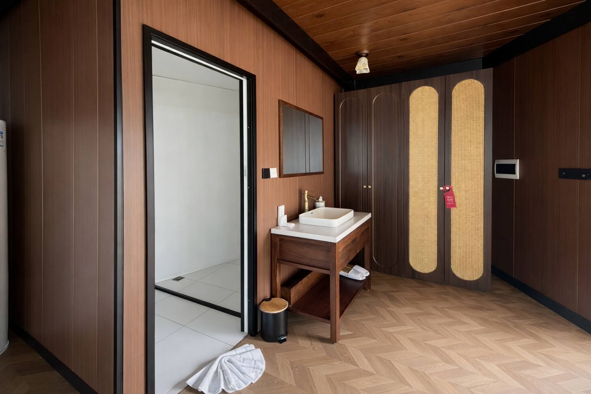 Un baño moderno con tocador de madera, un espejo grande y un inodoro empotrado.