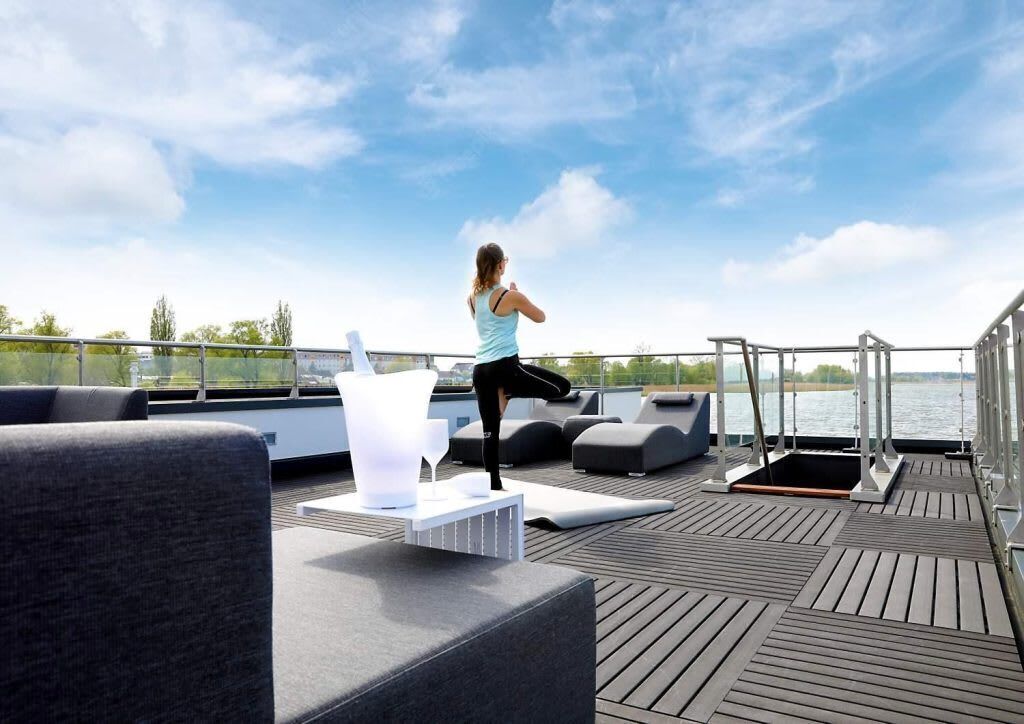 A person exercising on a deck with outdoor furniture and a view of the water.