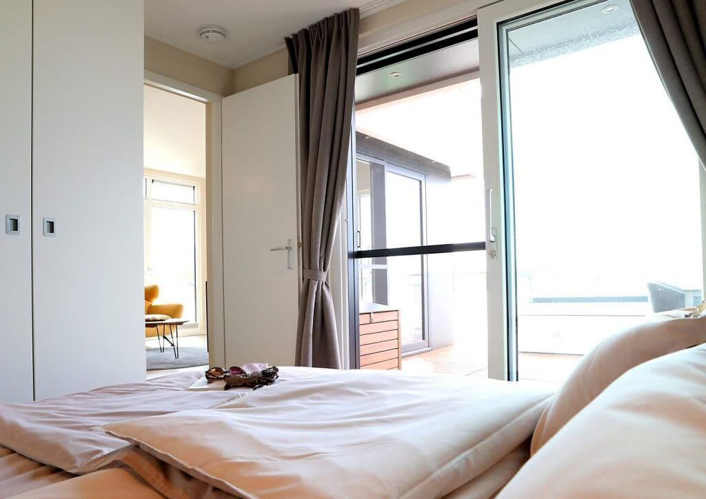 Ein Hotelzimmer mit Bett, einem Fenster mit Vorhängen und Blick nach draußen.