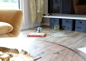 Ein Wohnzimmer mit einer Couch, einem Fernseher und Puzzleteilen auf dem Boden.