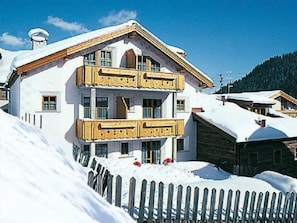 A multi-story building with a wooden balcony, surrounded by snow. - Appartements Lärchenhof, (Samnaun-Compatsch) by Interhome (Samnaun)