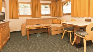 Un espace de vie compact comprenant un canapé, une petite table, une table à manger avec des chaises et un téléviseur.