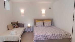 A small, single-room accommodation with a bed, a small table with a lamp, and two wall-mounted lights. - 100 meters from the ocean—apartment for 3 people (Santa-Maria-di-Lota)