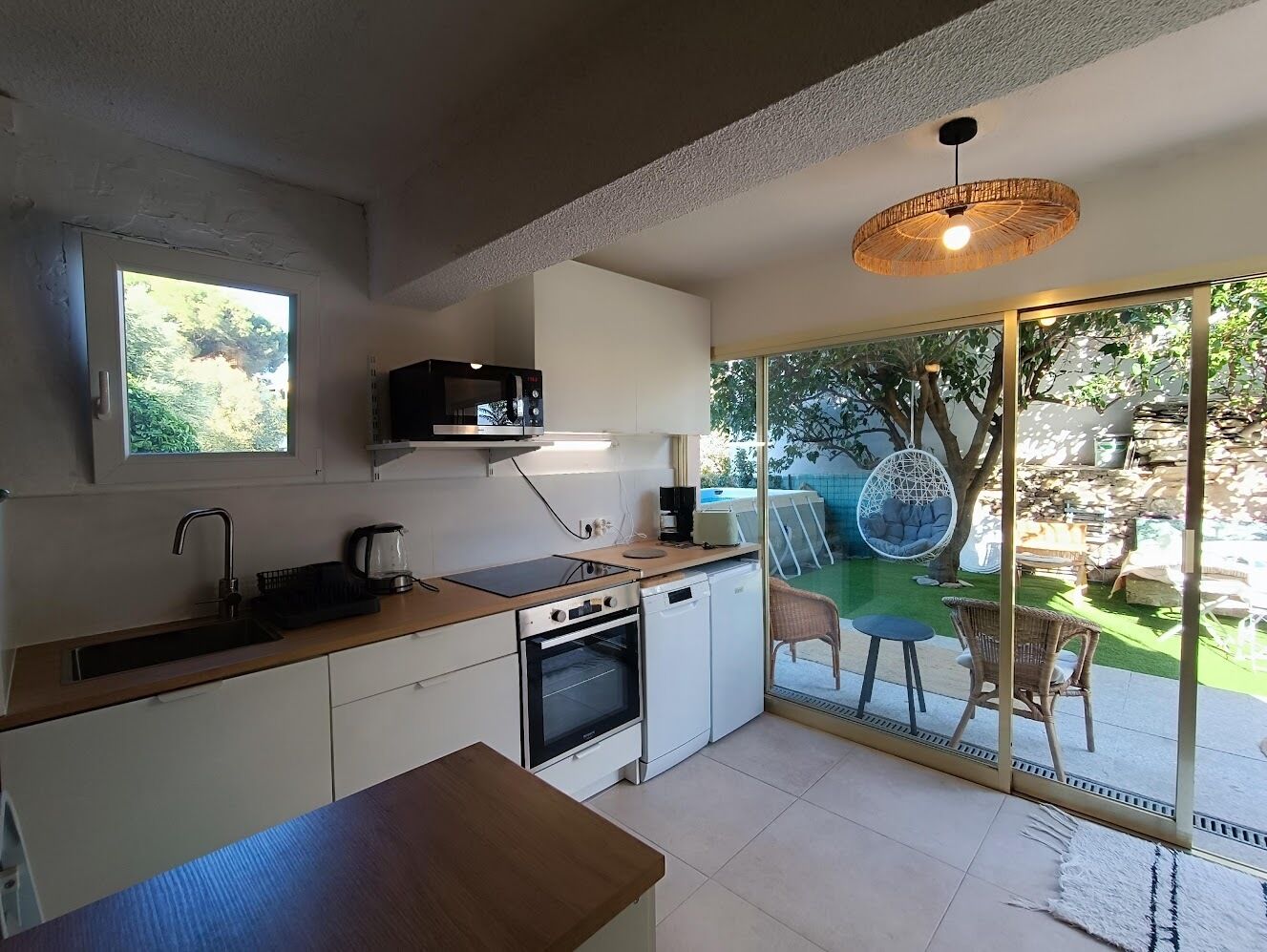 A compact kitchen with a microwave, stove, and sink. There is a dining area with a table and chairs.