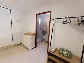 A room with a white wardrobe, a radiator, a wooden door, and a clothing rack with hangers. - 100 meters from the ocean—apartment for 3 people (Santa-Maria-di-Lota)