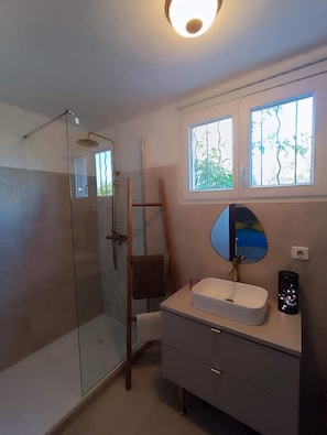 A bathroom with a glass shower enclosure, a wooden ladder, a sink with a mirror, and a window with a view of trees. - 100 meters from the ocean—apartment for 3 people (Santa-Maria-di-Lota)