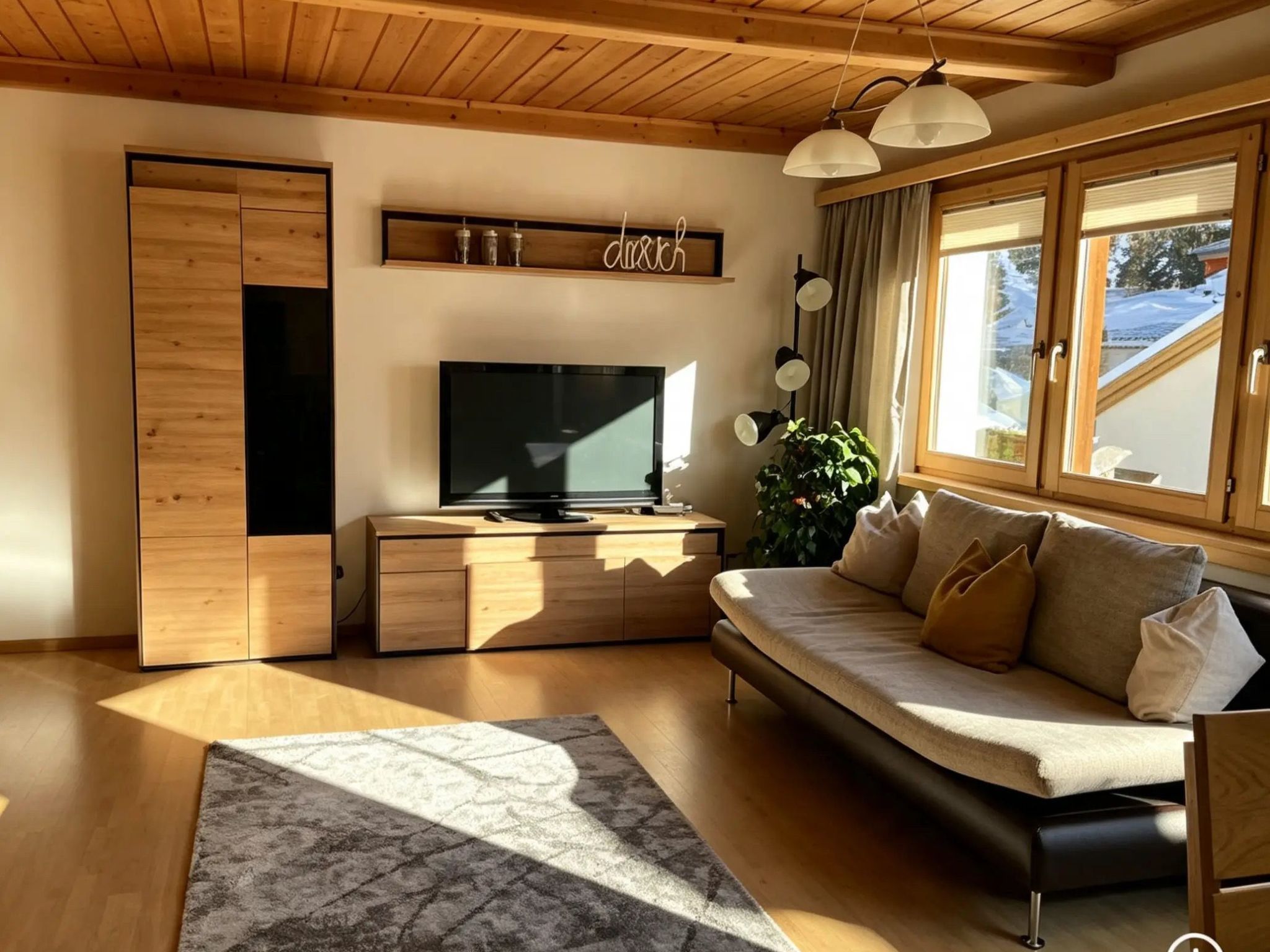 Un salon moderne avec un canapé, un téléviseur, un meuble en bois et une grande fenêtre avec des rideaux.