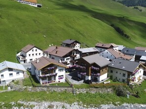 Un barrio residencial con casas, una calle pavimentada y una colina cubierta de hierba al fondo.