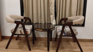 Un comedor con una mesa redonda y dos sillas, cada una con asiento y respaldo acolchados.