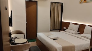 Habitación de hotel con cama, mesita de noche, silla y aire acondicionado.