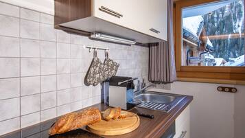 Una cucina con un piano di lavoro in legno, una pagnotta, un tostapane e una finestra con vista su un paesaggio innevato.