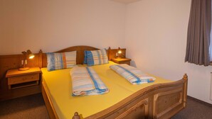 A double bed with a wooden headboard, two bedside tables with lamps, and a window with curtains.