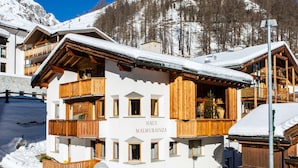 A multi-story hotel with wooden balconies and a sign that reads 'HAUS MALMURAINZA'.