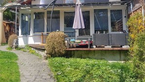 Ein Haus mit überdachter Terrasse, Solaranlage und einem Gartenweg.