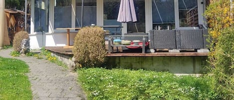 Una casa amb terrassa coberta, panells solars i un camí de jardí.