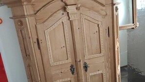 Ein hölzerner Kleiderschrank mit zwei Türen und einer kleinen Schublade, in einem Raum mit Fliesenboden.