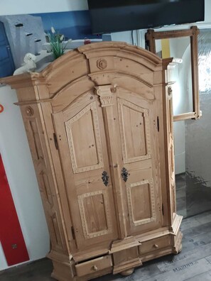 Un armario de madera con dos puertas y un cajón pequeño, en una habitación con piso de baldosas.