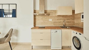 Cozinha compacta com lava-louças, máquina de lavar e painel de parede de madeira.