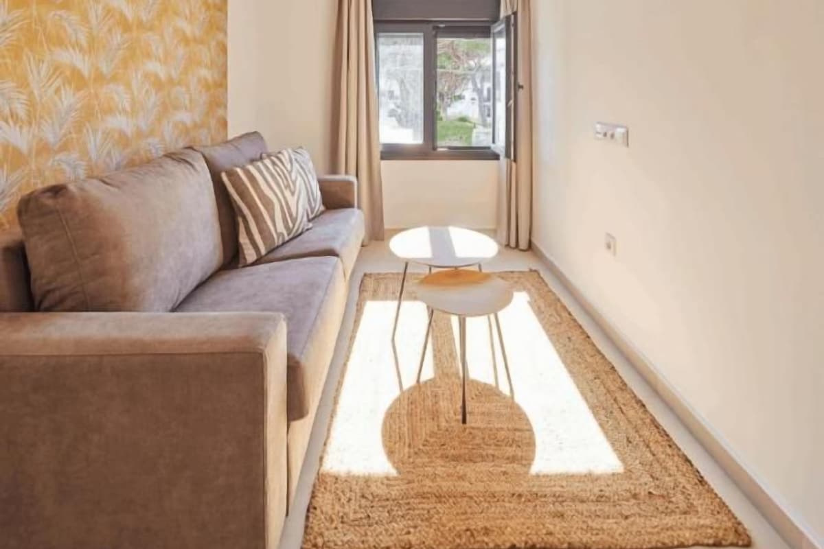 A modern living room with a sofa, a small round table, and a large window.