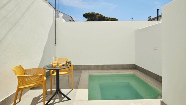 Uma pequena área externa com piscina, duas cadeiras e uma mesa.