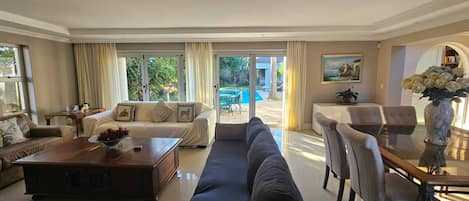 A spacious living room with a sofa, a coffee table, and a dining area with chairs and a table.