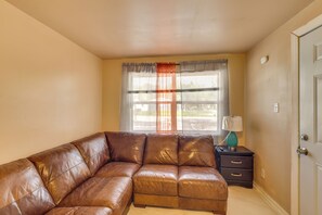 A room with a brown leather sofa, a small table with a lamp, and a door. - Tampa Group Escape: 3 Units Near Downtown (Tampa)