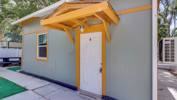 A small, single-story building with a white door, a window, and a yellow roof. - Tampa Group Escape: 3 Units Near Downtown (Tampa)