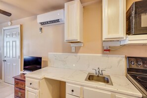 A kitchen with a marble countertop, a stove, a sink, and a TV on a wooden cabinet. - Tampa Group Escape: 3 Units Near Downtown (Tampa)