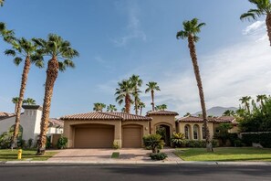 A residential area with multiple houses featuring Mediterranean-style architecture, palm trees, and a clear sky. - Canyon House at PGA West | Poolside Golf Views (La Quinta)