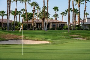 A golf course with sand bunkers, a flagstick, and palm trees. - Canyon House at PGA West | Poolside Golf Views (La Quinta)