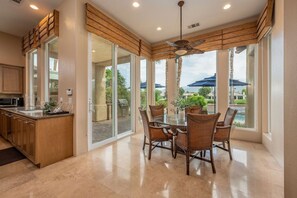 A kitchen with a dining area, large windows, and a ceiling fan. - Canyon House at PGA West | Poolside Golf Views (La Quinta)