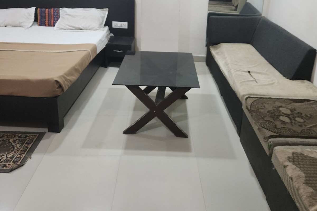 Un dormitorio con cama, mesita de noche y sofá.
