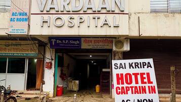 A building with a sign for Vardaam Hospital and a sign for a hotel named Sai Kripa.