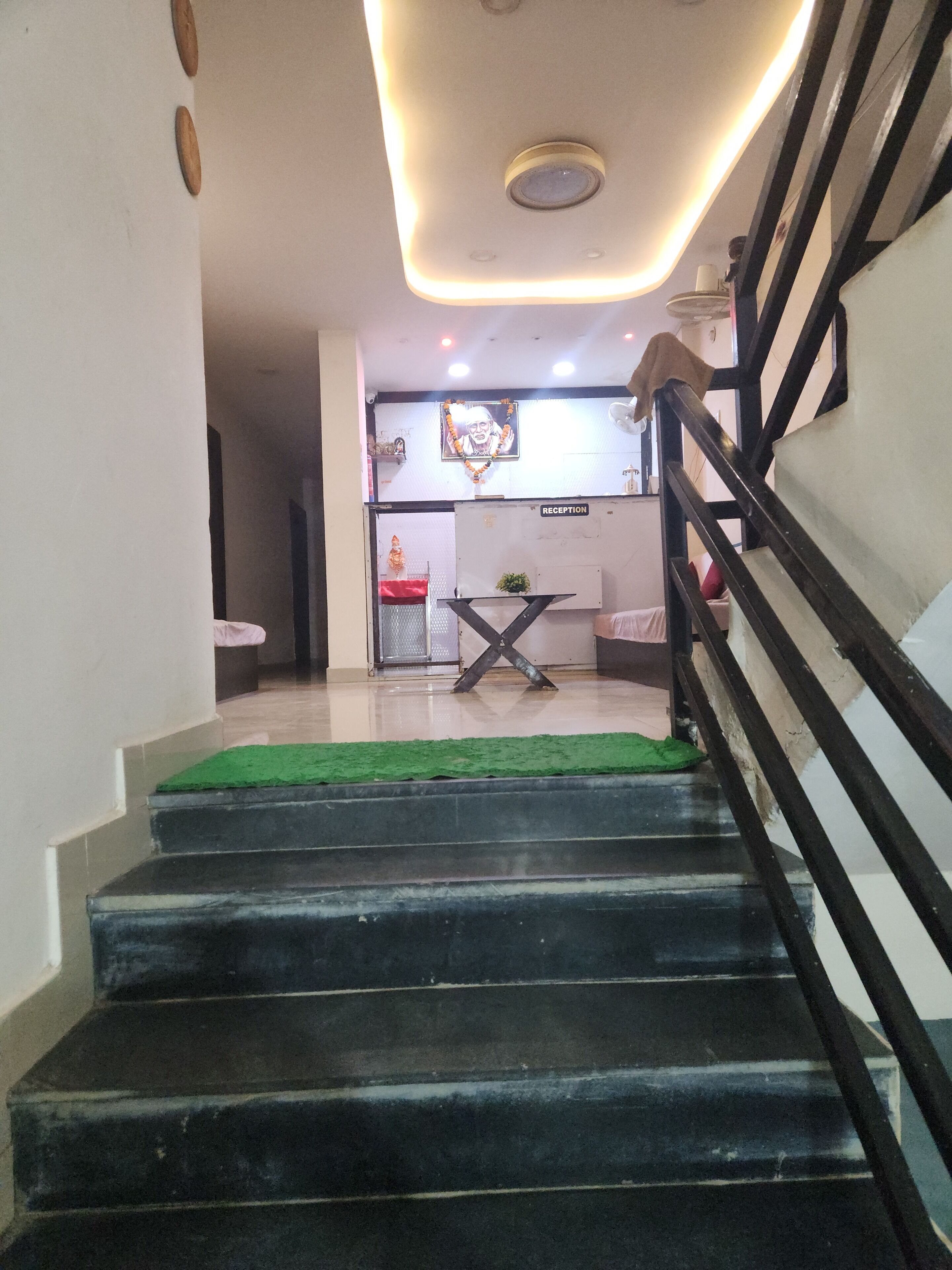 A staircase leading to a reception area with a sign, a small plant, and a ceiling light fixture.
