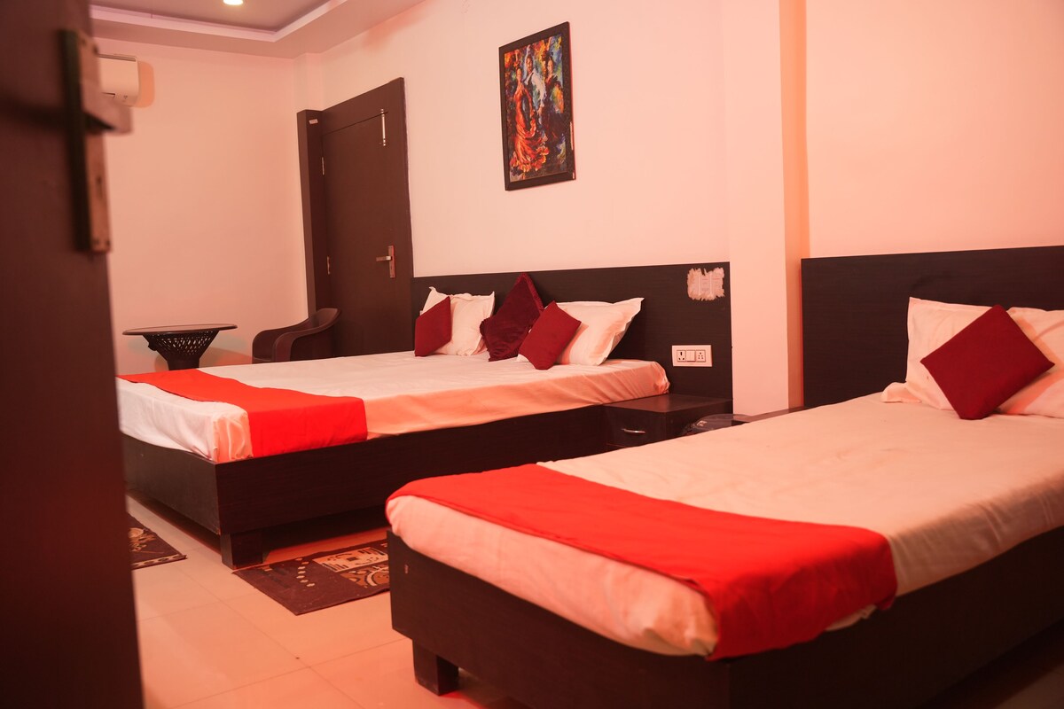 Habitación de hotel con dos camas, una puerta, un cuadro en la pared y una mesita.