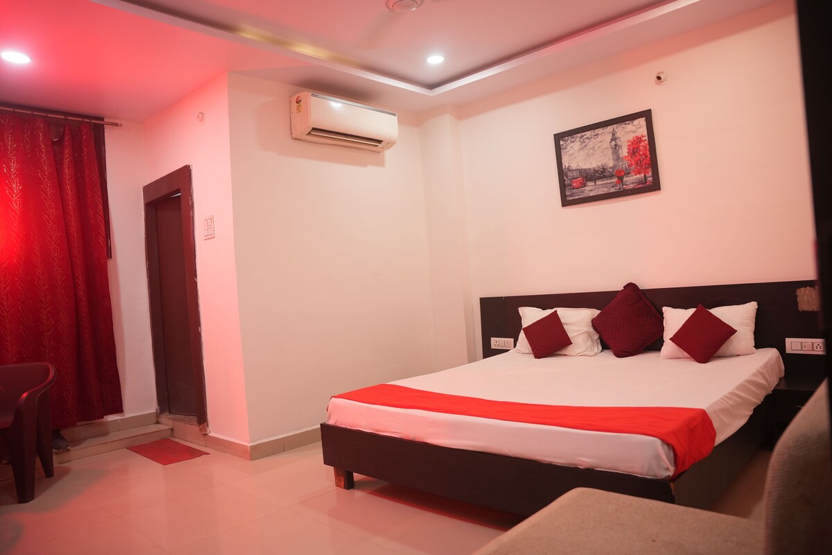 Habitación de hotel con cama, una silla, unidad de aire acondicionado y un cuadro en la pared.