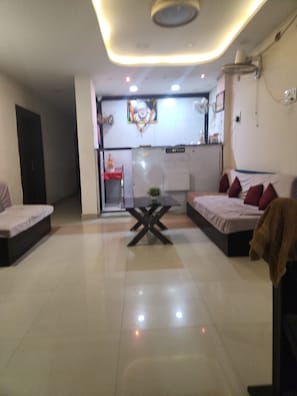 Una habitación moderna con dos camas, una mesita y una kitchenette al fondo.