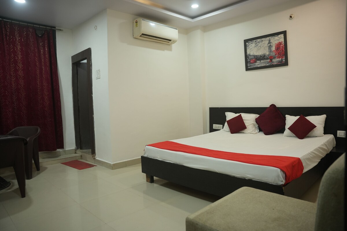 Habitación de hotel con cama, una silla, equipo de aire acondicionado y un cuadro en la pared.