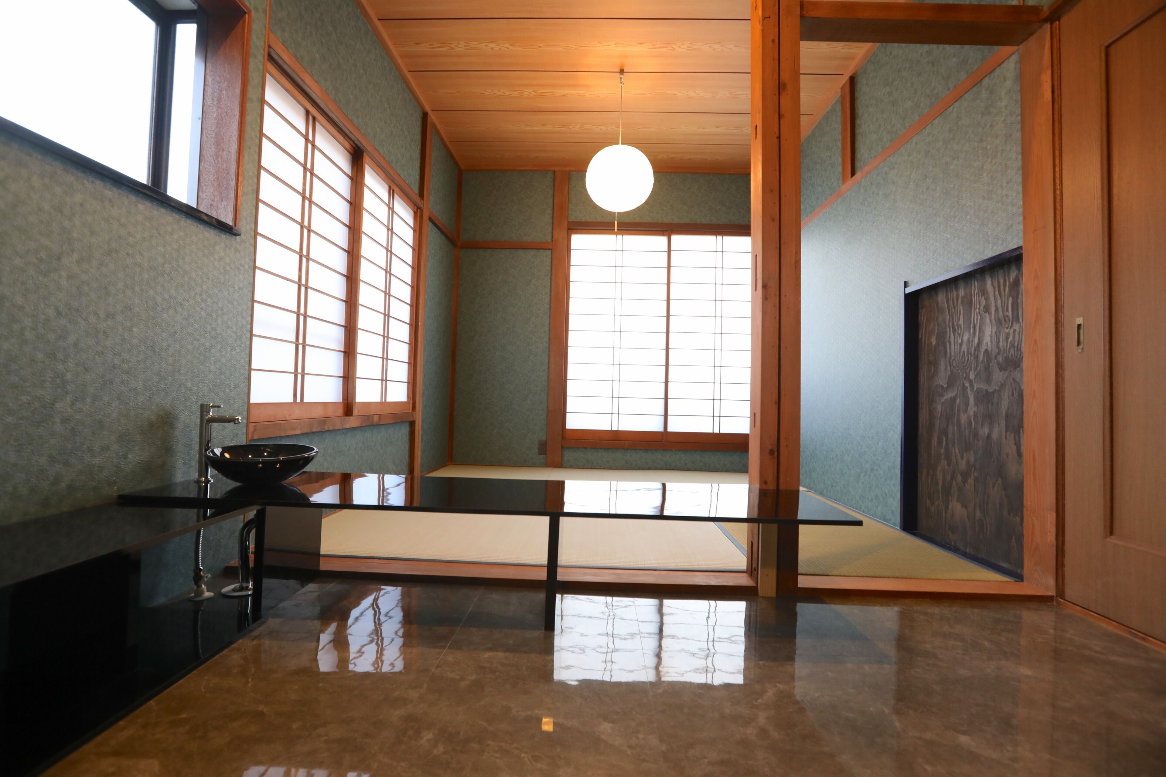 A traditional Japanese room with tatami flooring, sliding doors, and a black sink.