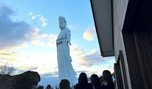 A large white statue in front of a building with a clear sky and some clouds. - Keshiki Tatsukane | Vacation Rental for Large Groups: BBQ & Karaoke (富津市)