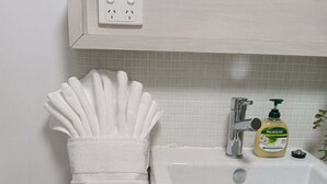 A bathroom with a white sink, a towel rack with a folded towel, a soap dispenser, and a power outlet on the wall. - Great family holiday home at Magnetic Island where adventure and fun starts. (Nelly Bay)