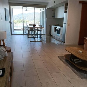 A modern kitchen with a built-in oven and a dining area with a table and chairs. - Great family holiday home at Magnetic Island where adventure and fun starts. (Nelly Bay)