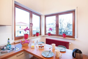 Una cocina con encimera de madera, una tetera y una ventana con vistas a edificios y árboles desnudos.