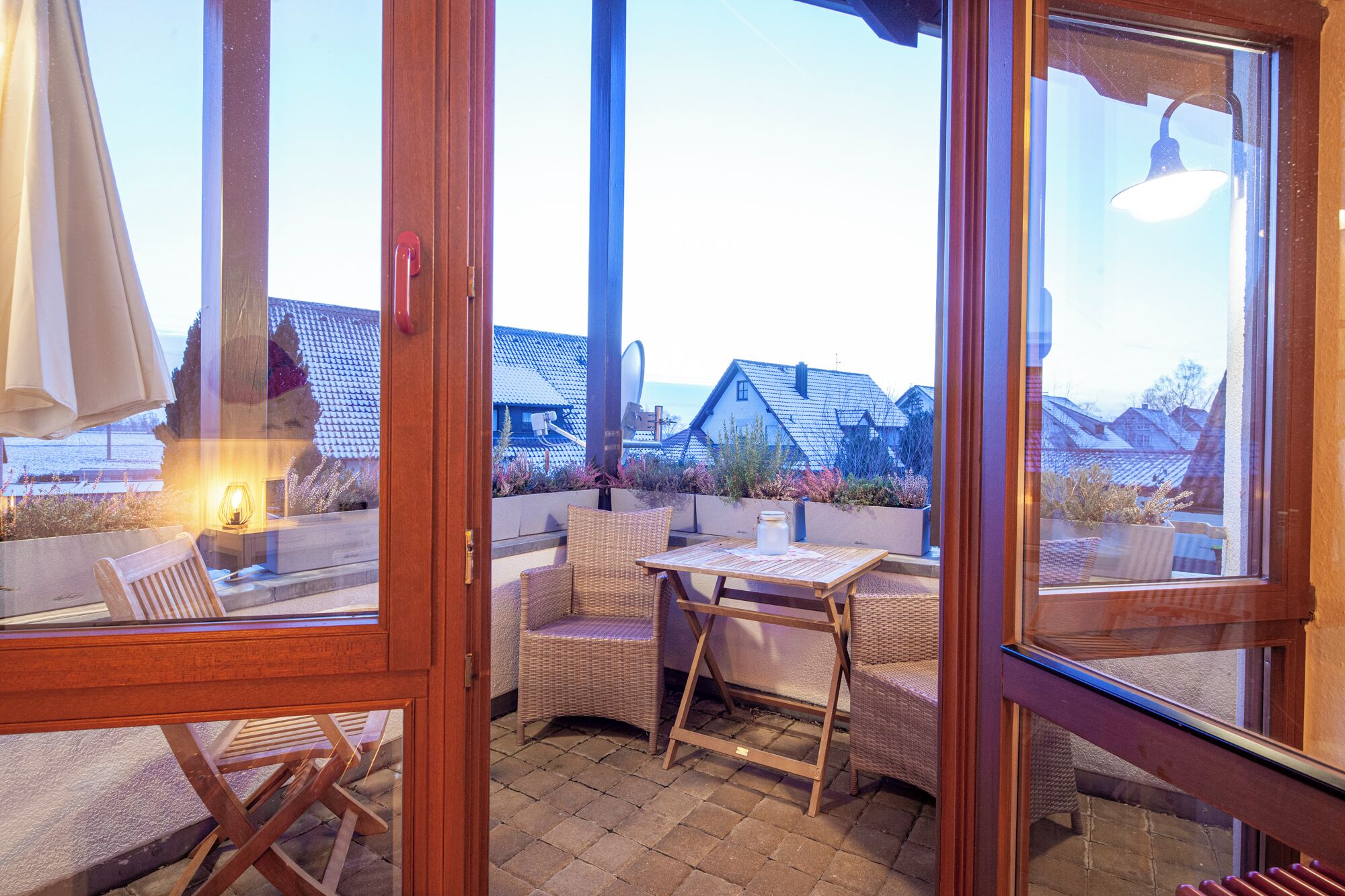 Un patio con mobiliario de mimbre, una mesa y vistas a casas al fondo.