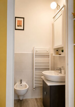A bathroom with a bidet, a sink, a mirror, and a towel rack. - Room-natures Retreat - Private Room - N (Florence)