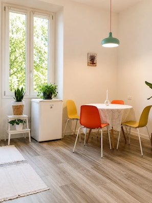 A dining area with a table, chairs, a small refrigerator, and potted plants. - Room-natures Retreat - Private Room - N (Florence)