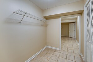 A hallway with a metal drying rack, a door with louvered shutters, and a tiled floor. - Kennesaw Home Near KSU & Lake Acworth (Kennesaw)