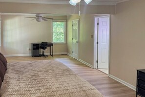 Une chambre à coucher comprenant un lit, un bureau, une chaise, un ventilateur de plafond et une fenêtre.